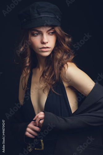 Girl on a black background. Low key. Nice young girl in a hat on a black studio background.