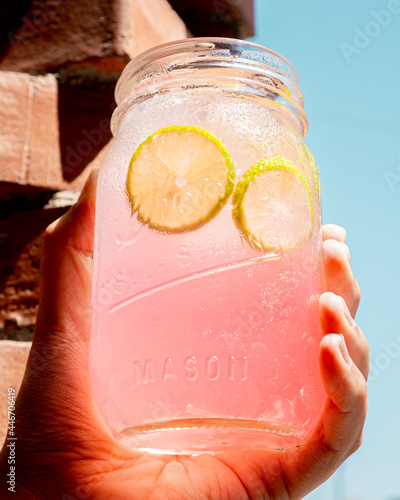 Refreshing pink lemonade held in one hand.