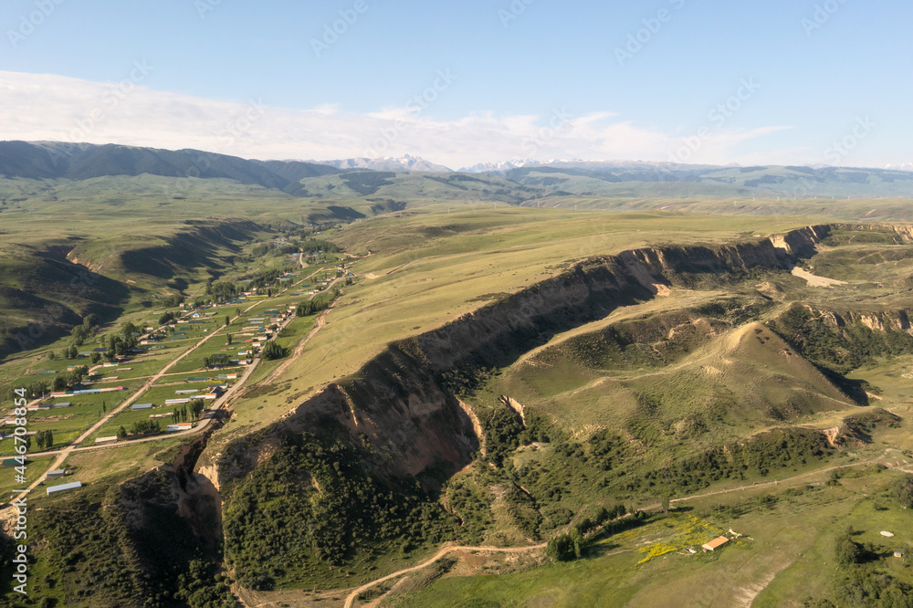 Naklejka premium Mountain peaks and grassland are under white clouds.