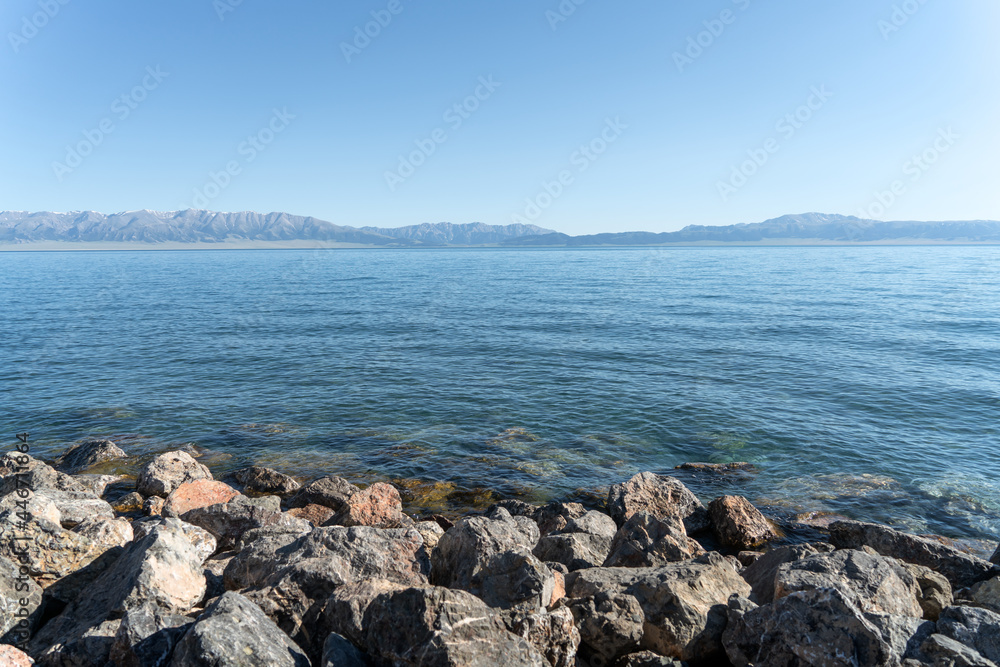 The calm surface of the lake and rocks. Shot in Sayram Lake in Xinjiang, China.