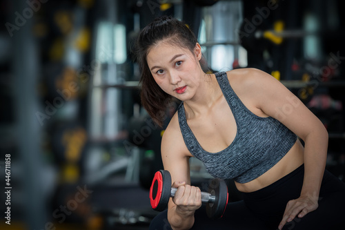 Sport woman doing exercises with dumbbell at gym ,she exercise for good healthy , bodybuilding and muscle.