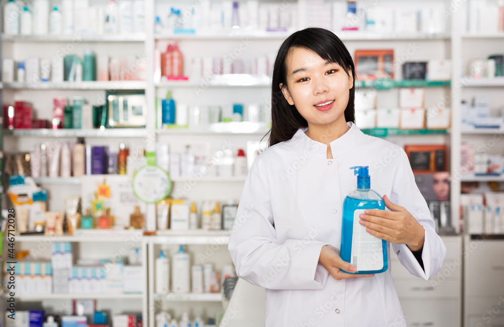 Positive chinese female pharmacist demonstrating assortment of drugstore