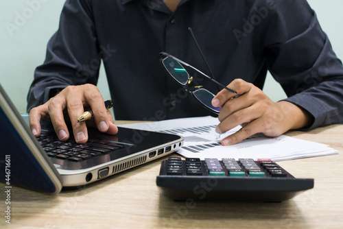 businessman working with business documents on wooden office table with computer notebook and calculator