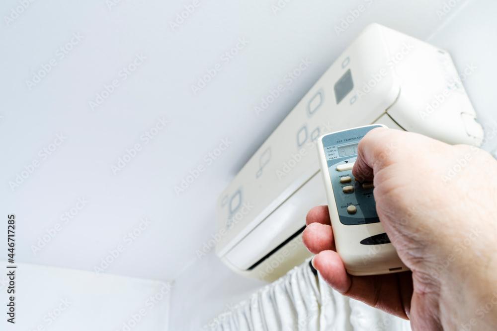 Hand of a man turning on an air conditioner with the remote control. Hand of a man turning on an air conditioner with the remote control.