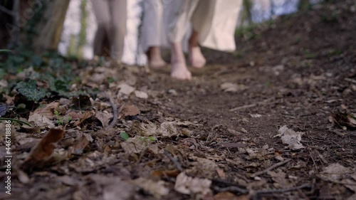 three women passing the camera on a path. They are wearing white robes and they are barefooted. photo