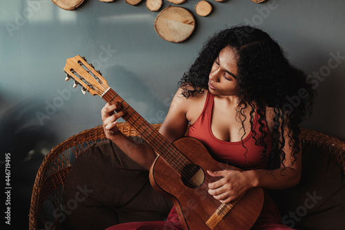 mujer negra de rizos con una guitarra tocando una melodía  photo