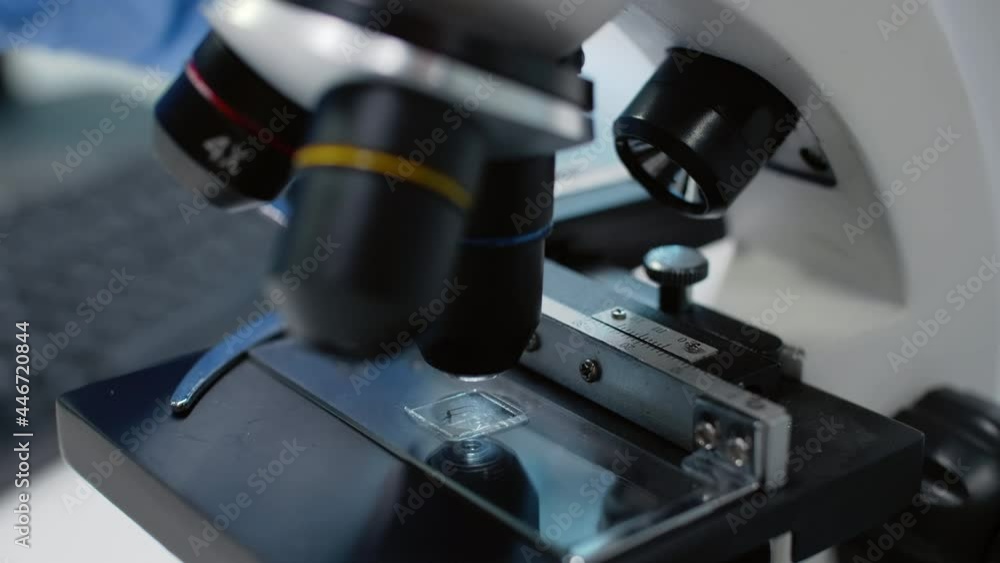 Close up of laboratory microscope with tray for fluid sample research at workplace. Optical instrument with magnifier and glass lenses or tools for genetic dna and blood substance Close up of laboratory microscope with tray for fluid sample research at workplace. Optical instrument with magnifier and glass lenses or tools for genetic dna and blood substance