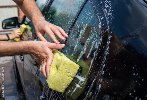 help wash the fender of the car with a washcloth on a sunny day in the garden after a flood,