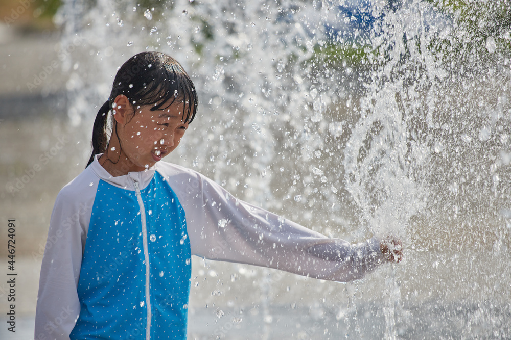 Fototapeta premium 真夏の公園の水エリアで遊んでいる可愛い女の子の様子
