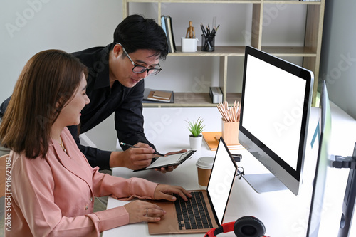 Two business colleagues using digital tablet to discussing information in modern office.