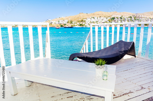 Relaxing Rattan Sunbed and White Wooden Table with Sea View .Private Beach above the Sea  photo