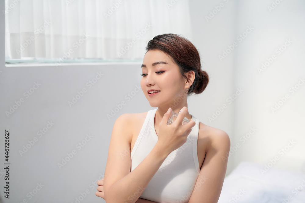 Young beautiful woman sitting against mirror and applying perfume Young beautiful woman sitting against mirror and applying perfume