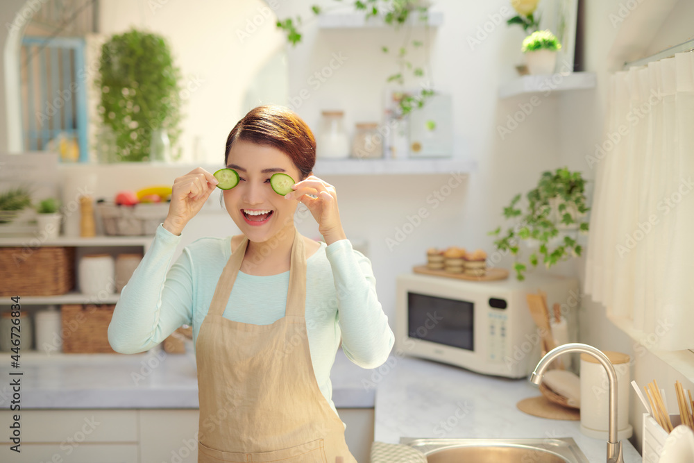 Young housewife playing with food cut slices of sweet cucumber while cooking in the kitchen. Young housewife playing with food cut slices of sweet cucumber while cooking in the kitchen.