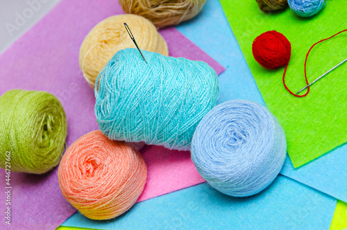 skeins of thread and a needle scattered on multi-colored foamiran paper, multi-colored skeins of thread
