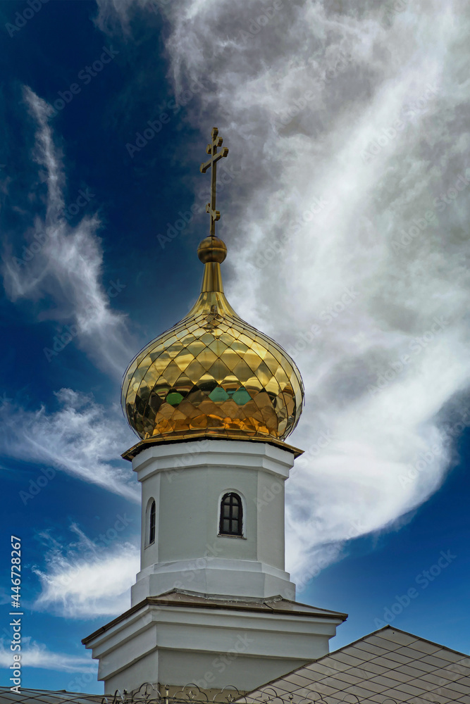 The dome of an Orthodox church against a blue sky with white clouds