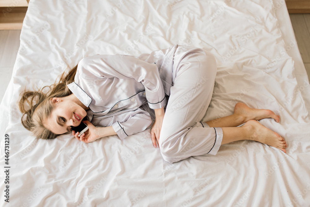Portrait young beautiful smiling woman lying in bed drinking her morning coffee dreaming.