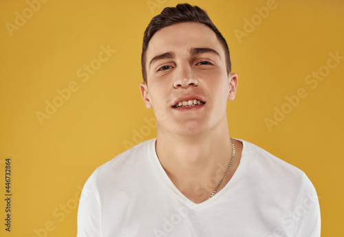 handsome man in white t-shirt confident look cropped view yellow background emotions © SHOTPRIME STUDIO
