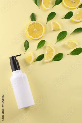 Topview of cosmetics skincare and cosmetic lotion bottle with lemon food fruit vitamin c herb extract on light yellow background.
 photo