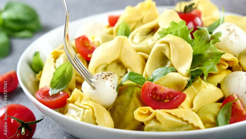 eating tortellini with mozzarella, tomato and basil eating tortellini with mozzarella, tomato and basil