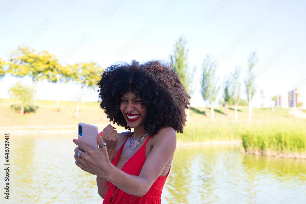 Beautiful afro american woman talking on video call is very happy. The woman is wearing a red top. Video call concept