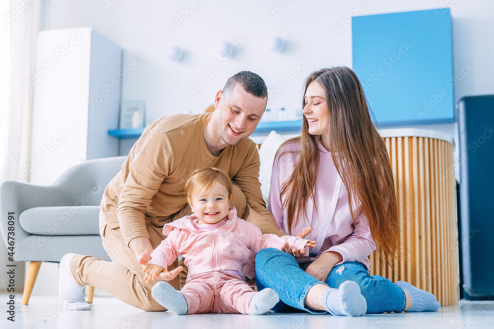 Happy family is sitting on the floor with their little child. th Happy family is sitting on the floor with their little child. th