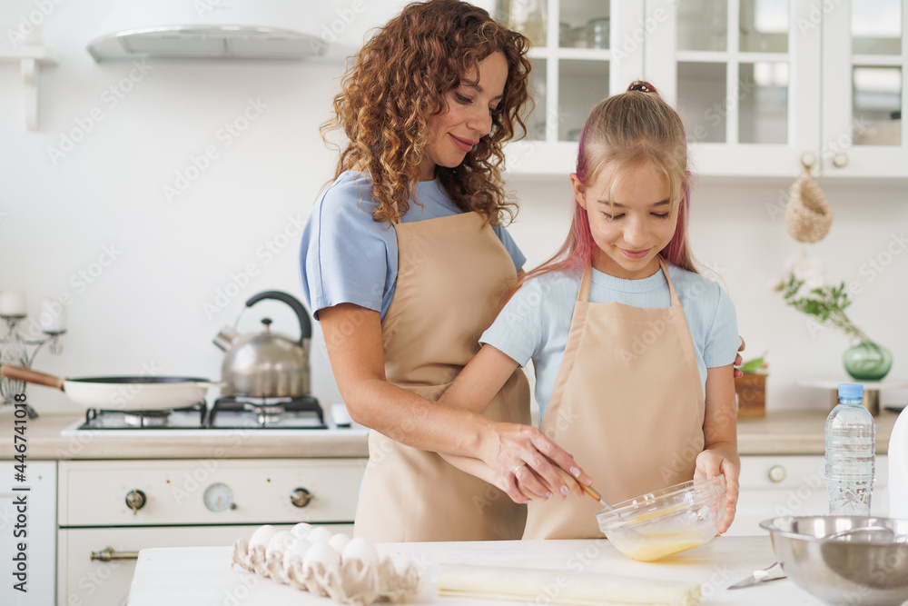 Mother and teen daughter making dough for pastry toghether in kitchen