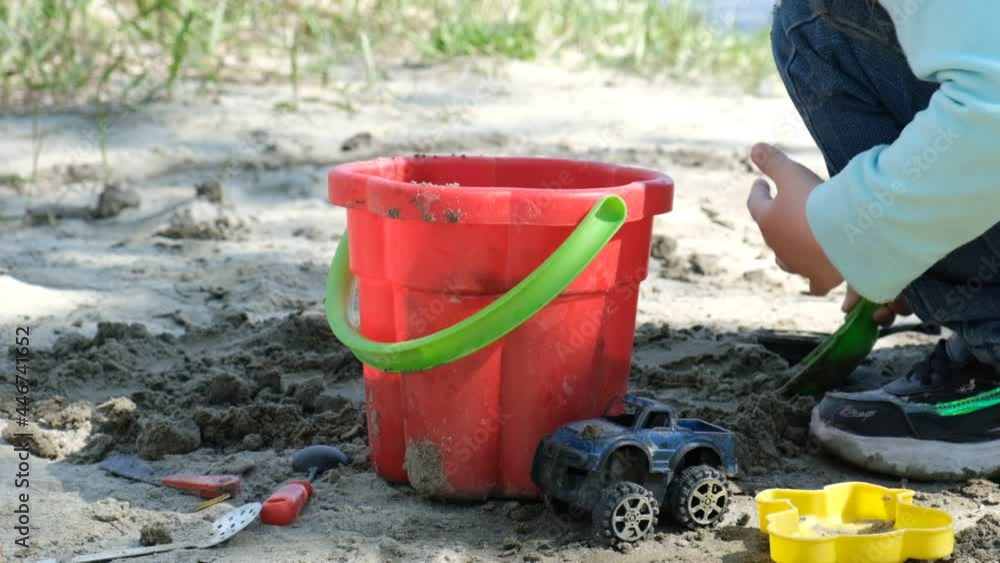 Concentrated toddler playing with his toy bucket and shovel near the river. Springtime and early morning. Investigate details of nature. outdoor kids activity and learning concept Concentrated toddler playing with his toy bucket and shovel near the river. Springtime and early morning. Investigate details of nature. outdoor kids activity and learning concept