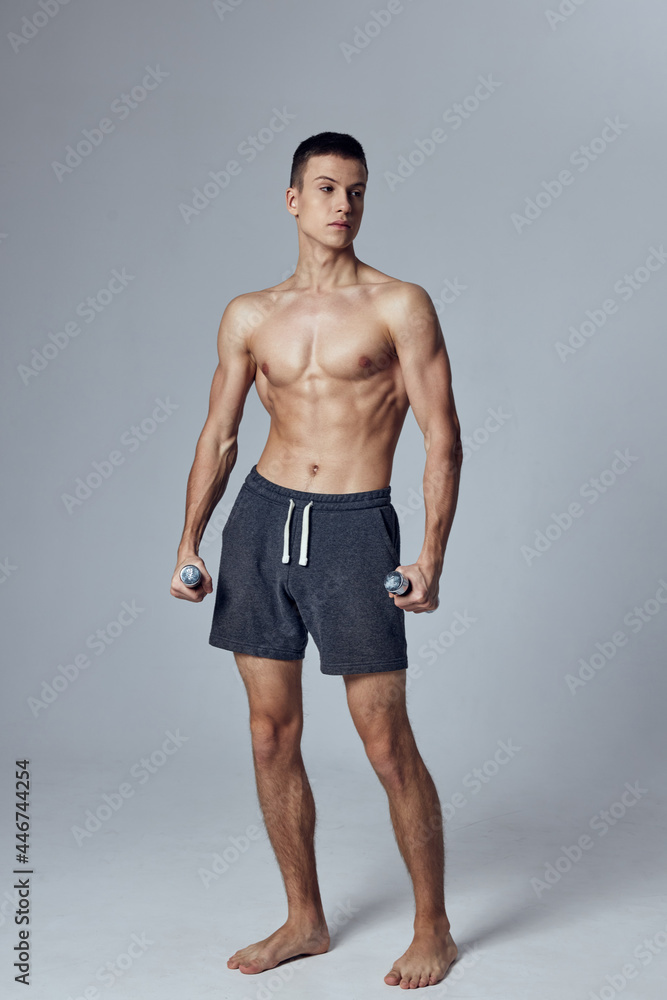 sporty man with pumped up muscular body gymnasium dumbbells in hands isolated background