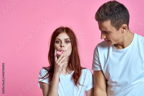 cheerful young couple in white t-shirts fun fashion pink background