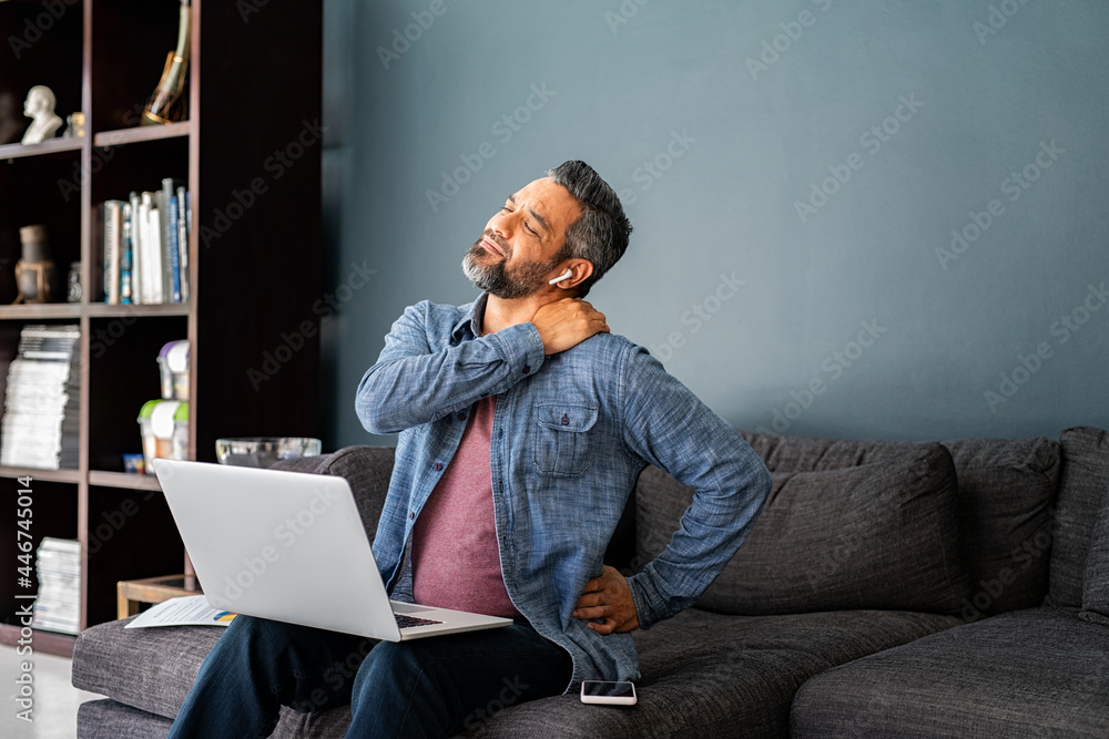 © Rido - Exhausted ethnic man stretching neck and back after many hours spent working