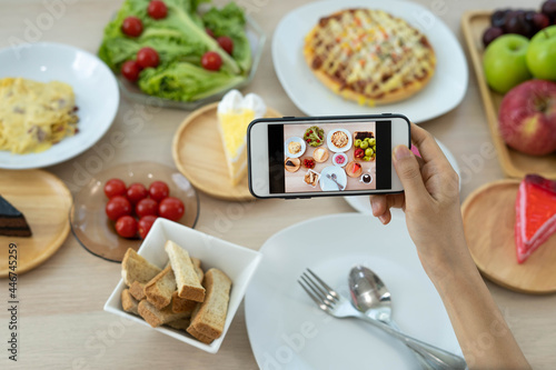 A man uses a mobile phone to open an app to take pictures of food at a table in a restaurant.