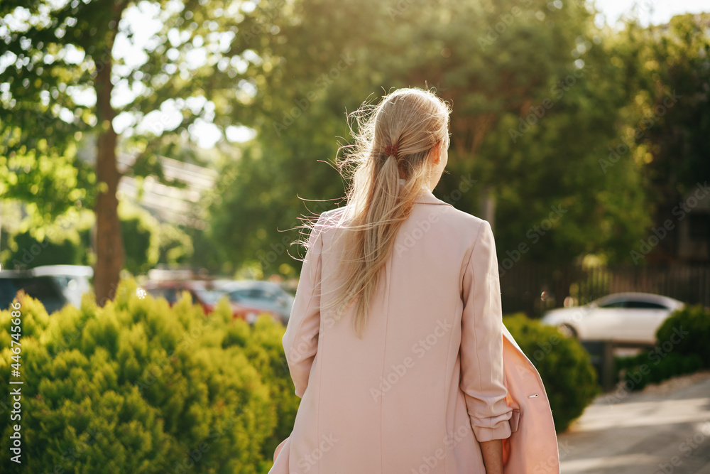 Stylish young businesswoman walking on the city street on sunny day