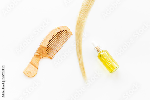 Hair essential oil with wooden comb and blond curl of hair