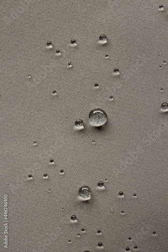 Round water drops on gray textured vertical background.