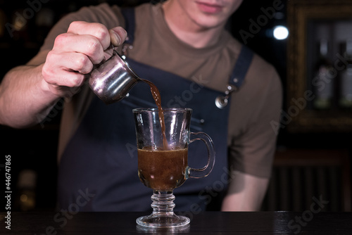 Close up hands of the bartender who make a cocktail. Irish coffee