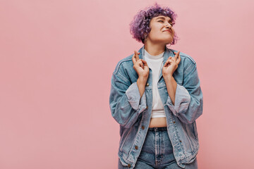 Curly charming woman in good mood and in bright clothes smiling. Cute adult girl in short top rejoices at something on pink background..