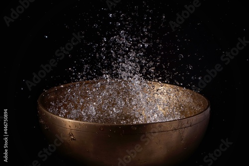 water droplets floating above the sound bowl against a black background 