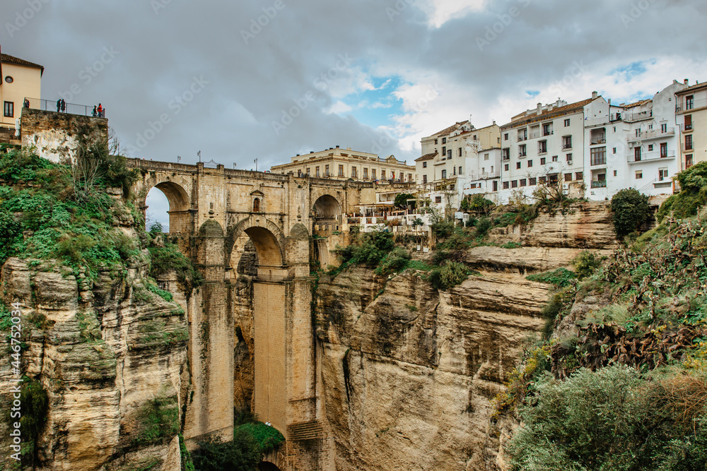 Gorgeous view of Ronda,Andalusia,Spain. Puente Nuevo New Bridge over Guadalevin River.Old Stone bridge,town at the edge of cliff with trees and white houses against sky.Wanderlust holiday concept.