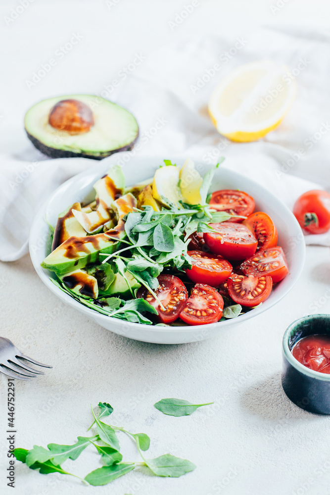 tomato salad arugula avocado lemon in white plate on light background tomato salad arugula avocado lemon in white plate on light background
