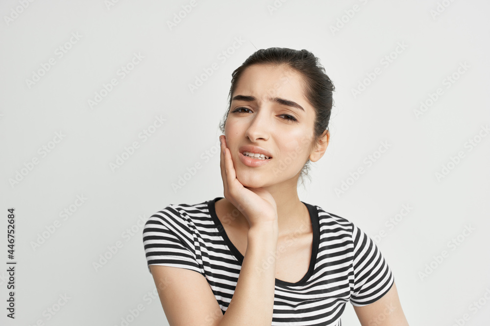 woman in striped t-shirt holds face pain in teeth dentist treatment woman in striped t-shirt holds face pain in teeth dentist treatment