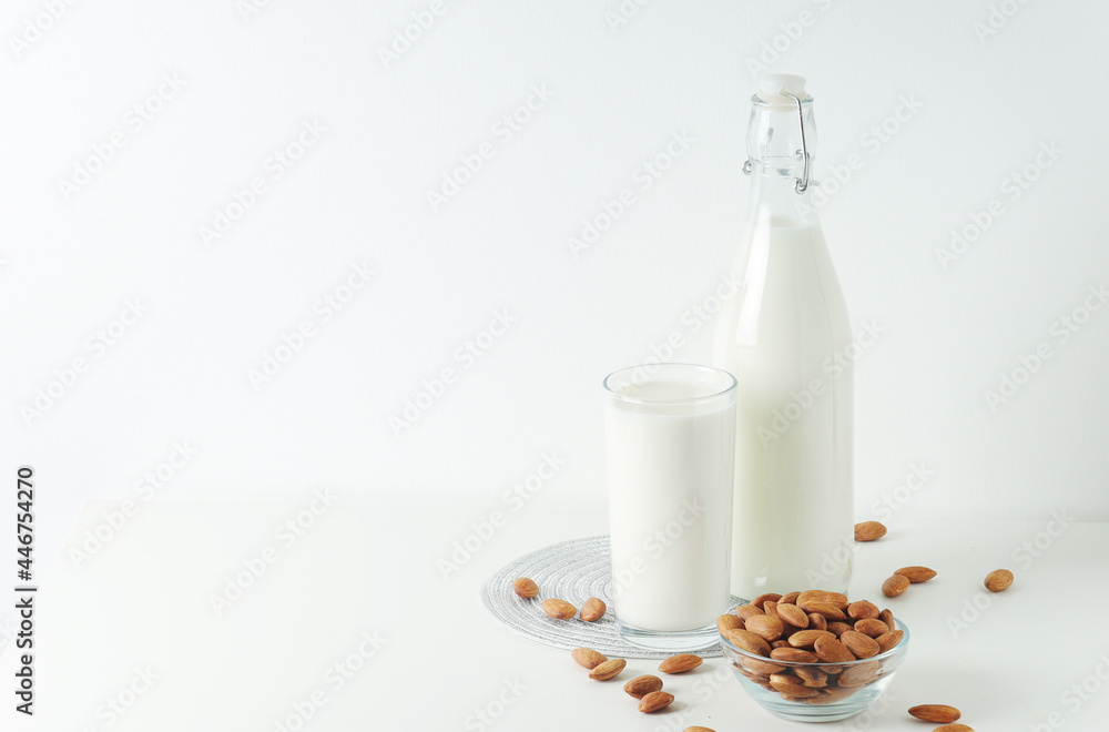 A glass with almond milk and the bowl with almonds A glass with almond milk and the bowl with almonds