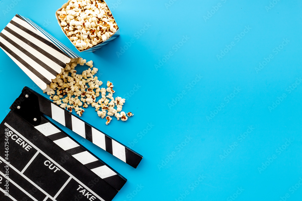 Popcorn with clapperboard and movie film reel. Cinema background