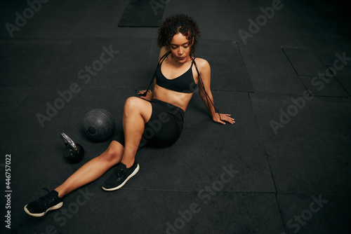 African American female athlete resting after an intense workout in the gym. African American woman holding skipping rope. High quality photo