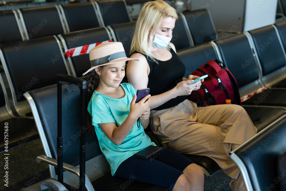 Mother and daughter with face mask going on holiday, at the airport Mother and daughter with face mask going on holiday, at the airport