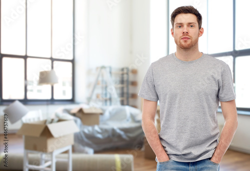 moving, real estate and people concept - young man in gray t-shirt and jeans over new home background