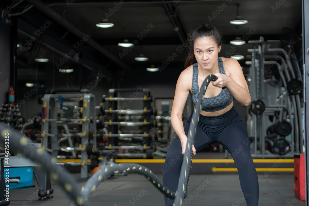 Powerful muscular woman exercising with battle ropes at the gym Powerful muscular woman exercising with battle ropes at the gym