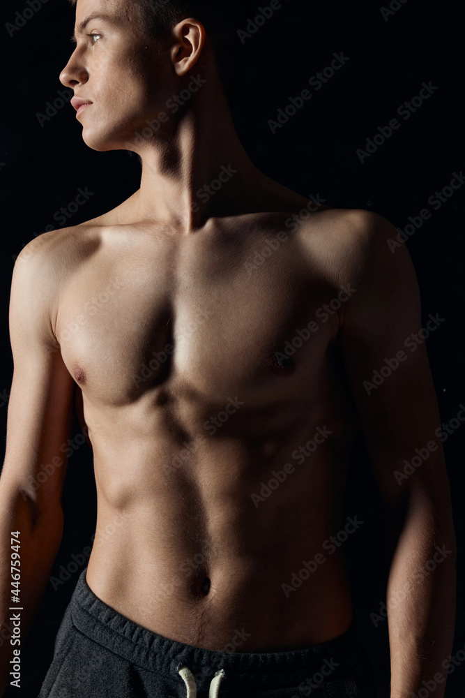 athlete with a naked torso looks to the side on a black background