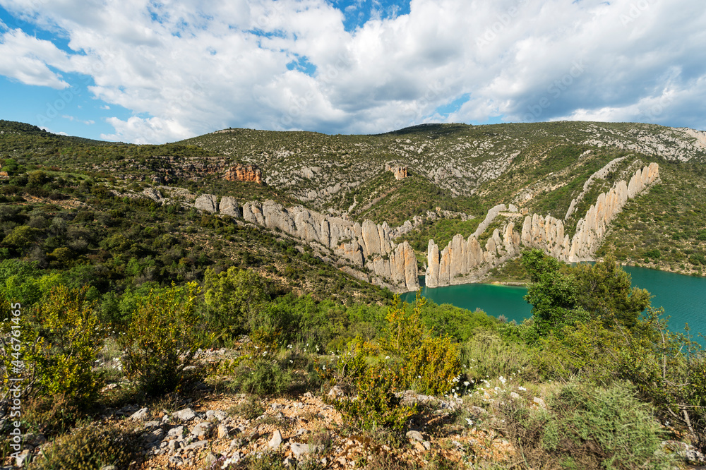 paisaje de una cordillera de piedras entre las montañas, con árboles y un estanque de agua en la base 