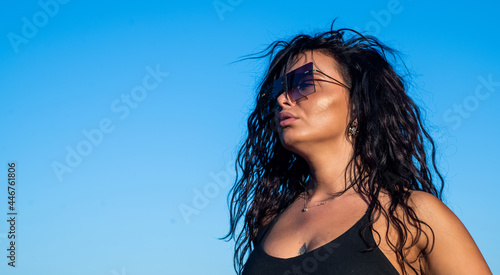 sexy brunette girl has long curly hair wearing stylish sunglasses and enjoy summer weather outdoor, fashion and beauty, copy space