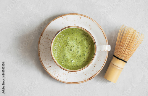 Matcha green tea. Homemade matcha latte and bamboo whisk on a gray concrete background closeup. Top view, flat lay.